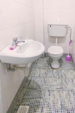 A bathroom with a white sink, toilet, and a tiled floor. - Meliva Guest House Mbarara (Mbarara)