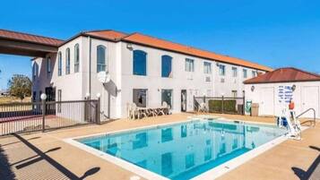Un bâtiment doté d’une piscine, d’un espace extérieur aménagé et d’une zone délimitée par une clôture.