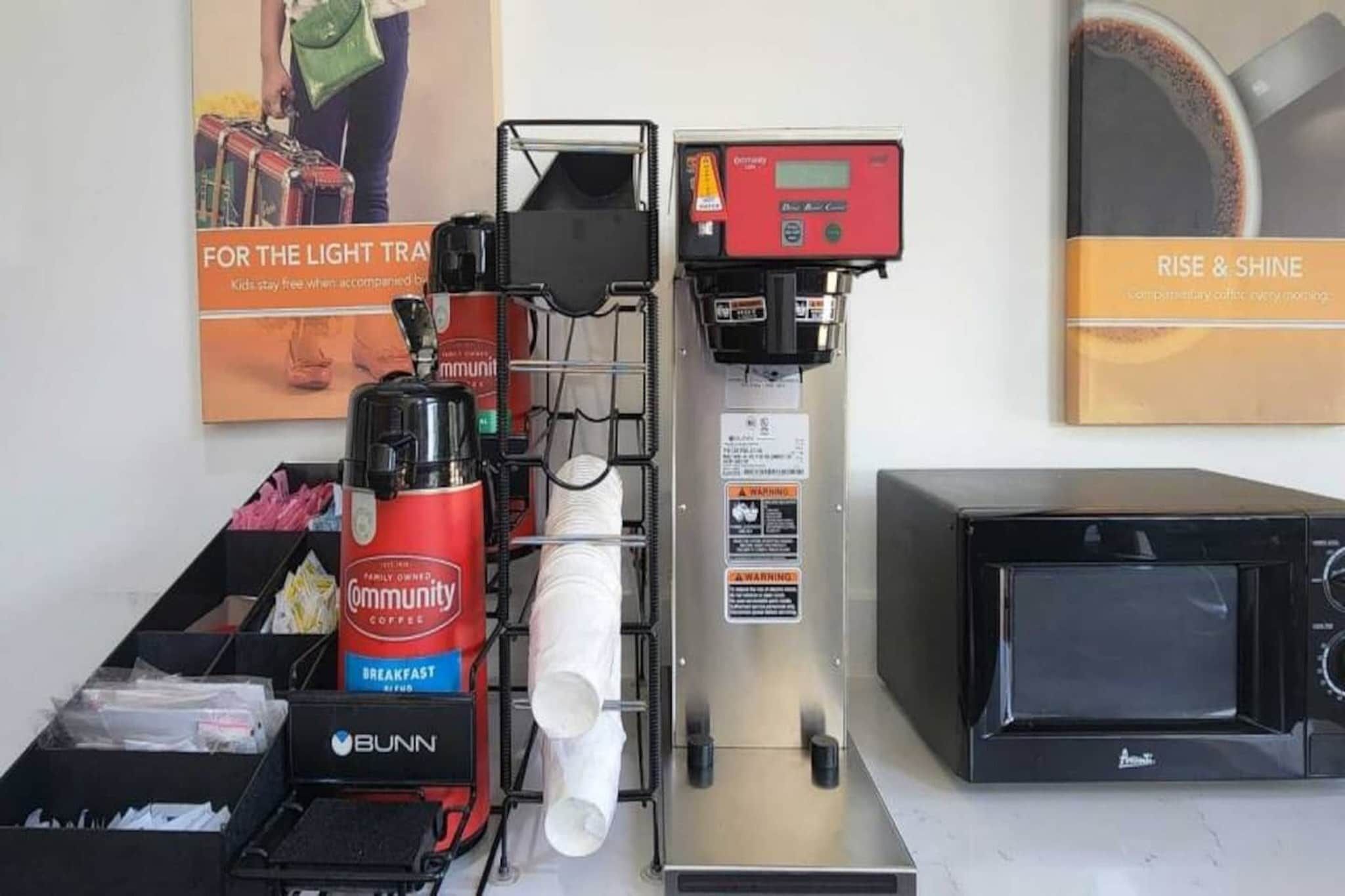 Una cafetera, un microondas y un molinillo de café en una zona de cocina.
