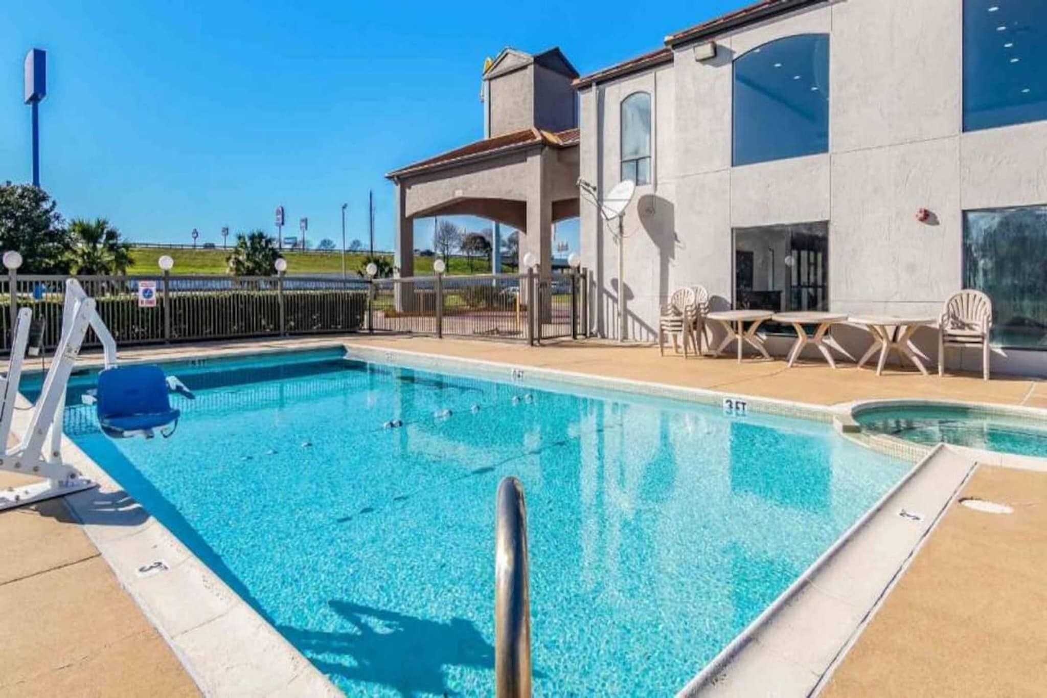 A swimming pool with a lifeguard chair, lounge chairs, and a covered seating area.