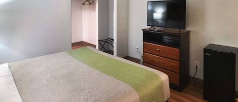 Habitación de hotel con cama, televisión, cómoda y escritorio.