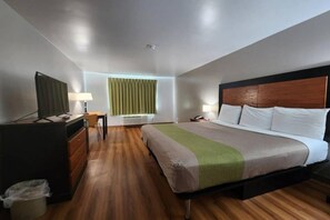 A hotel room with a bed, a desk, a chair, a TV, and a window with curtains.