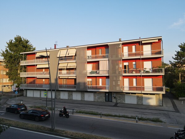 Ein mehrstöckiges Wohngebäude mit Balkonen, einer Garage und Blick auf die Straße.