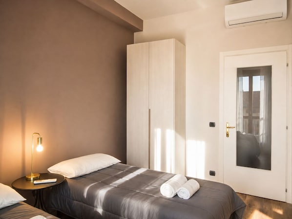 Une chambre moderne avec un lit, des tables de chevet, une armoire et une porte donnant sur une vue agréable.