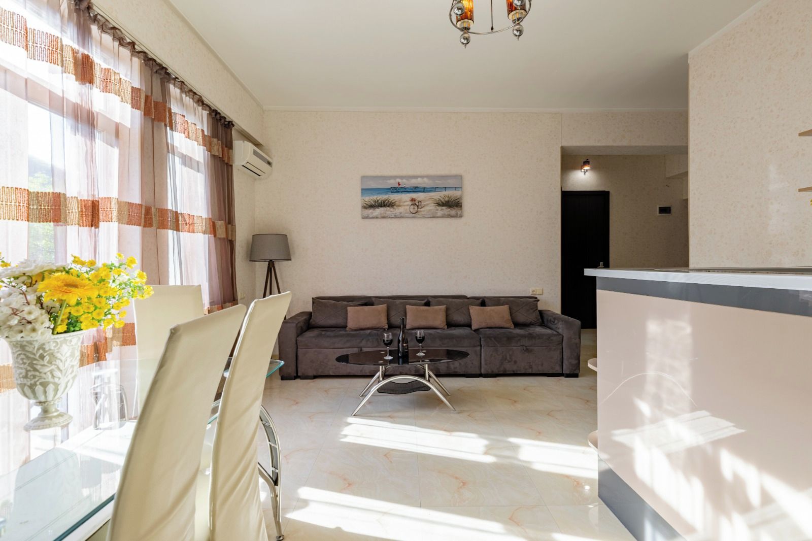 A living room with a sofa, a dining table, and a vase of flowers.