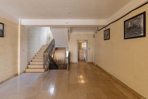 A hallway with a staircase, a door leading to an elevator, and a wall-mounted picture. - Prime Comfort Residence (Tbilisi)