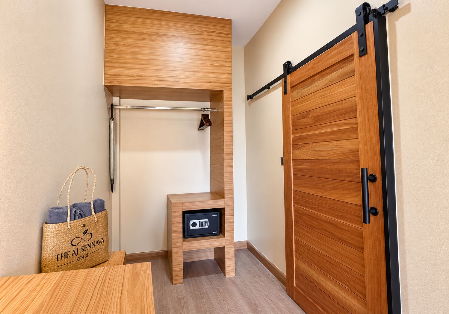 Una habitación con un armario de madera, una mesita de madera, un bolso tejido y un dispositivo en la pared.