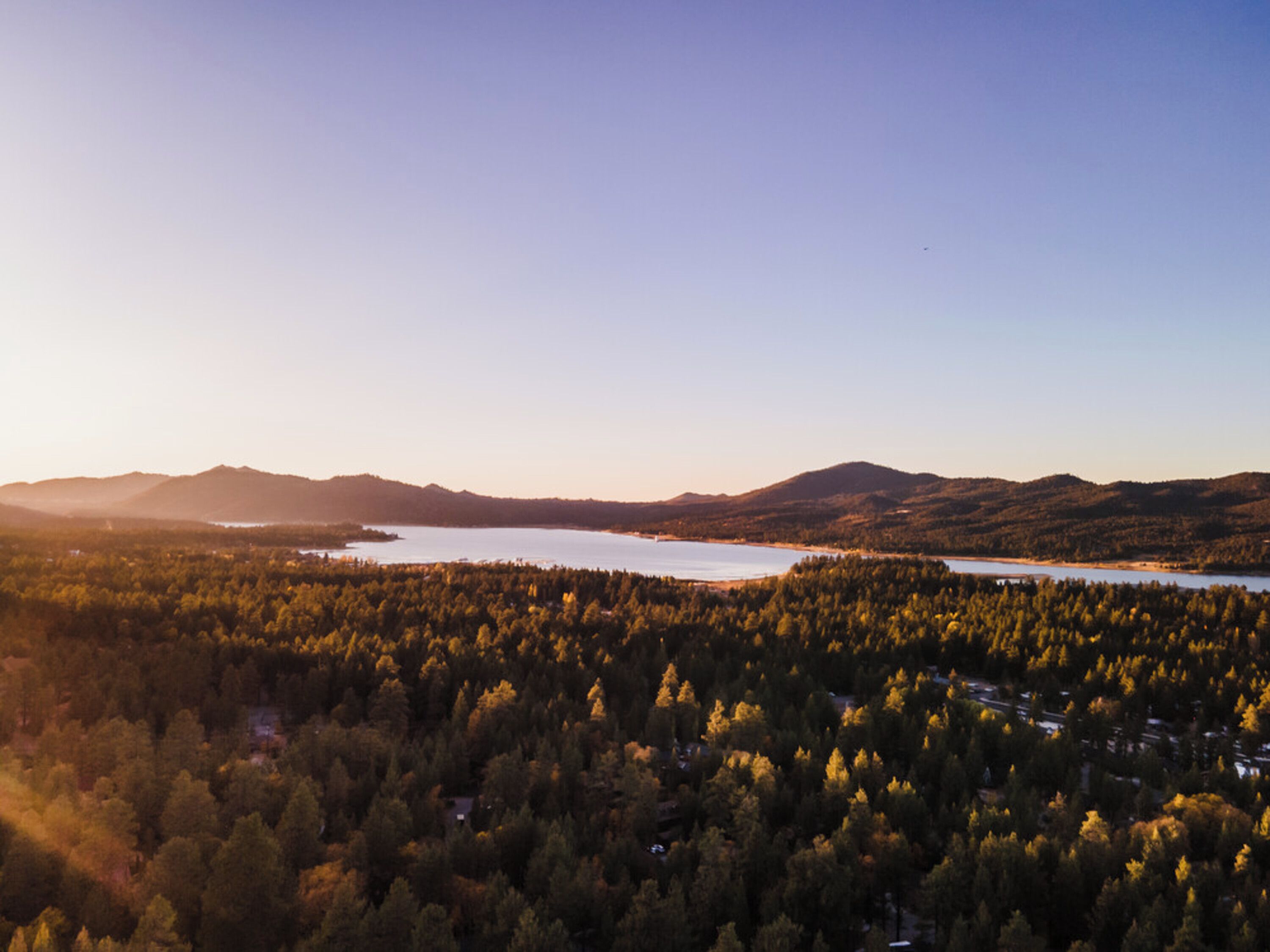 Vista panorámica de un paisaje montañoso con un lago y un bosque denso.