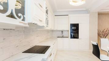 A modern kitchen with white cabinetry, a marble backsplash, and a built-in oven.