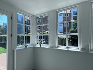 Habitación en esquina con ventanal que da a un edificio de ladrillo y un jardín.