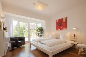 Une chambre à coucher avec un lit, un bureau, une chaise et une grande fenêtre.