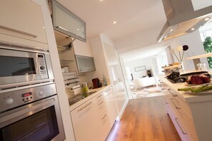 Une cuisine moderne dotée d’appareils électroménagers en acier inoxydable, de meubles blancs et d’un plancher en bois.
