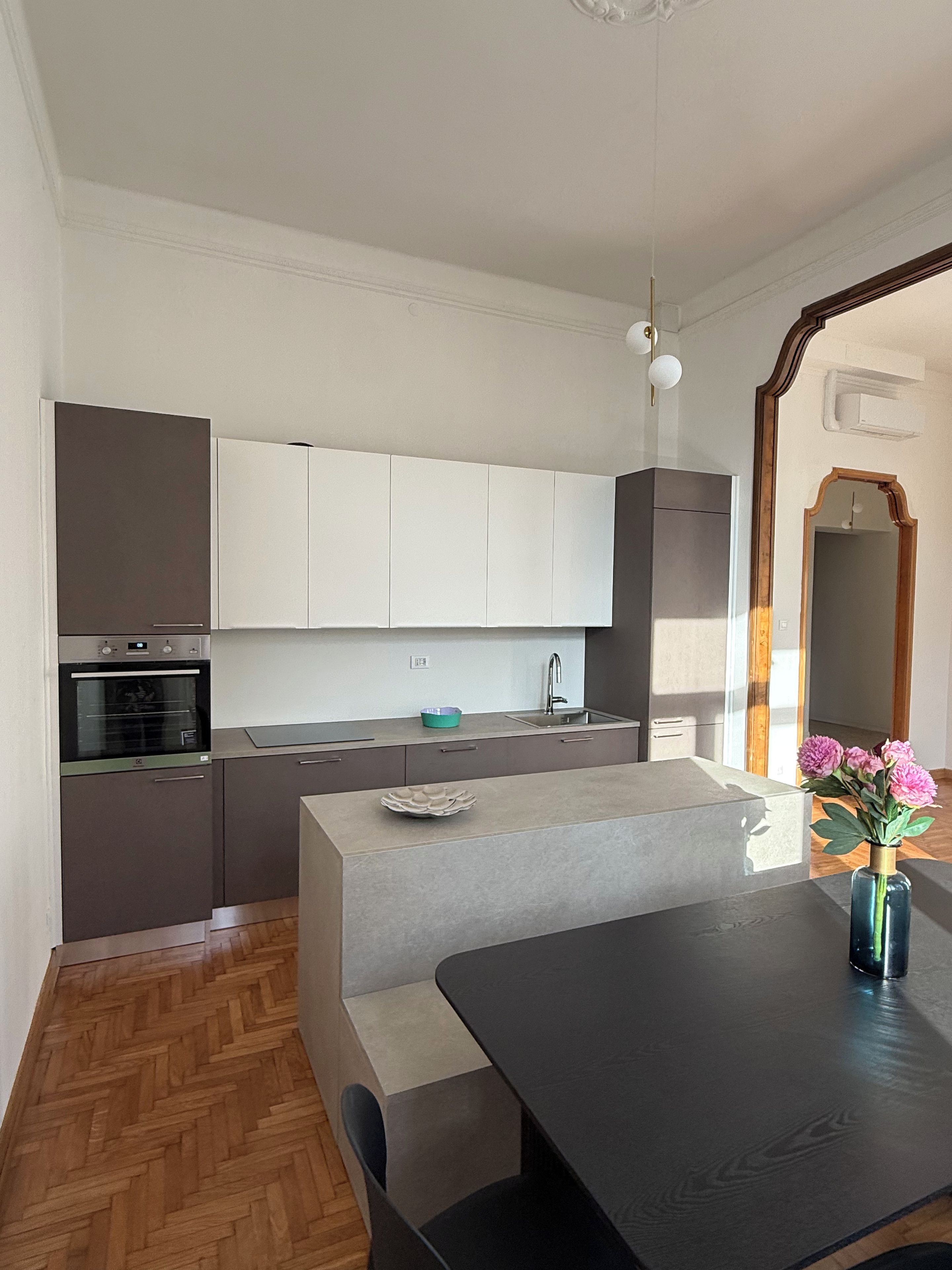 Una cucina moderna con isola centrale, elettrodomestici integrati e zona pranzo con tavolo e sedie.