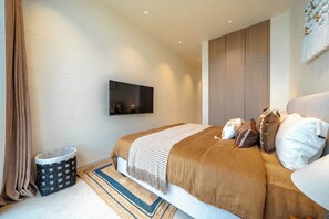Un dormitorio moderno con una cama grande, un televisor de pantalla plana en la pared y un armario empotrado.