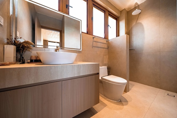 Un baño moderno con un lavamanos grande, espejo y ducha.