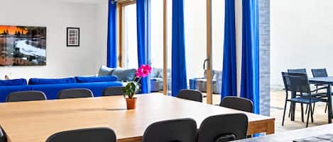 A modern dining area with a wooden table, black chairs, and a blue sofa.