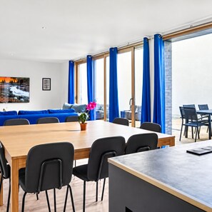 Un comedor moderno con una mesa de madera, sillas negras y un sofá azul.
