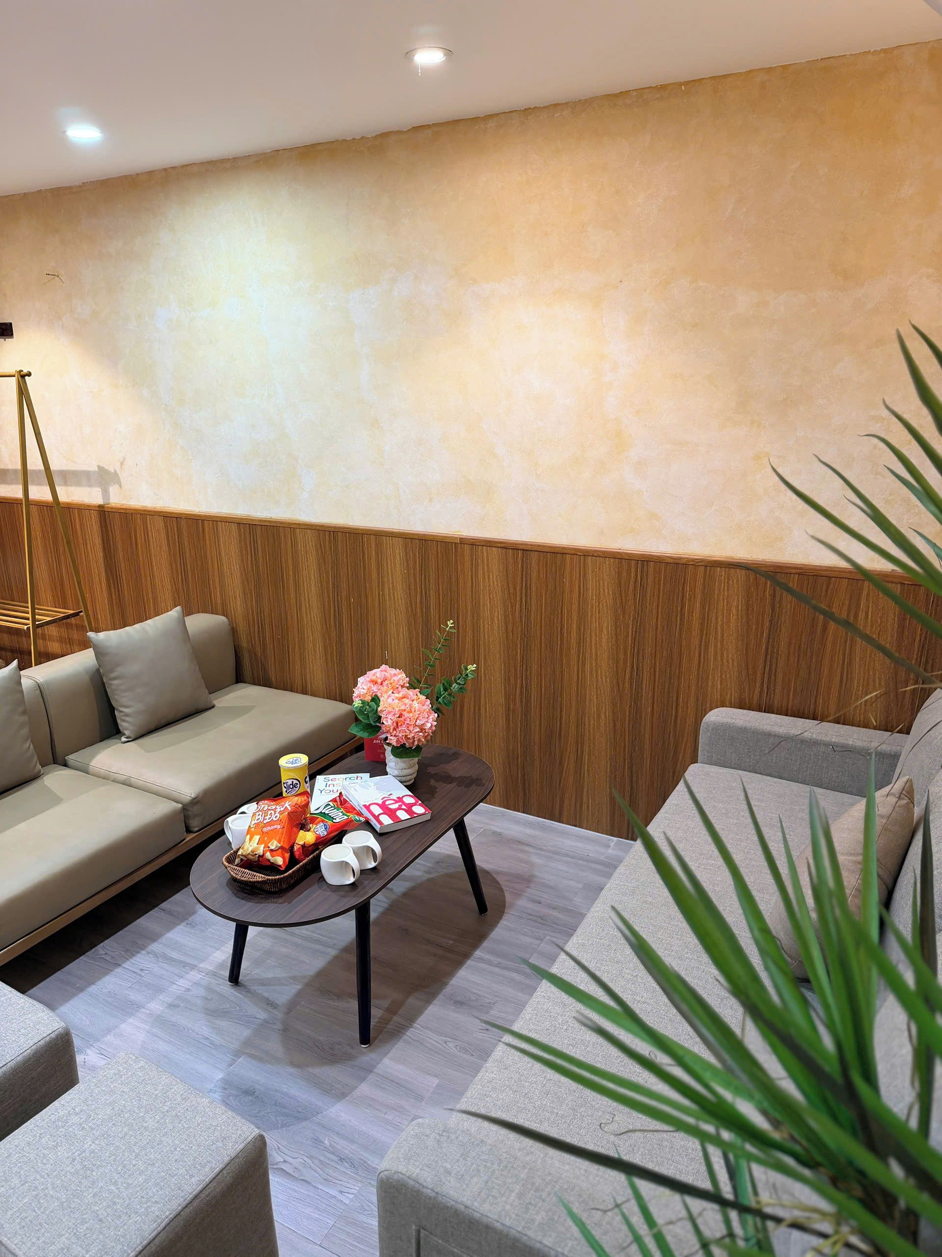 A modern living room with a sofa, a coffee table with snacks and drinks, and a wooden accent wall.
