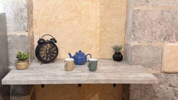 A stone archway with a shelf holding a clock, a teapot, and two cups.