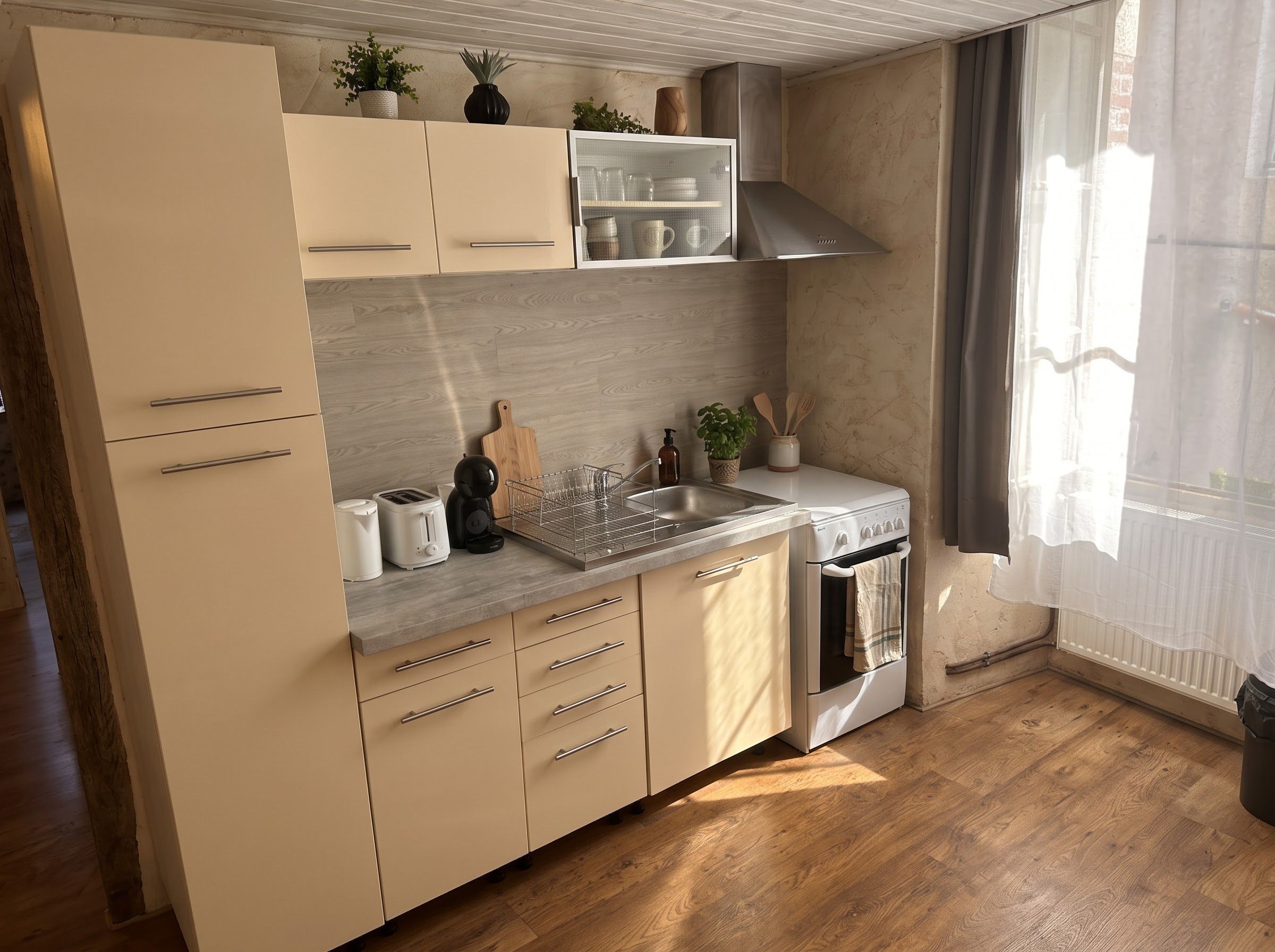 A modern kitchen with a wooden floor, stainless steel appliances, and a window with sheer curtains.