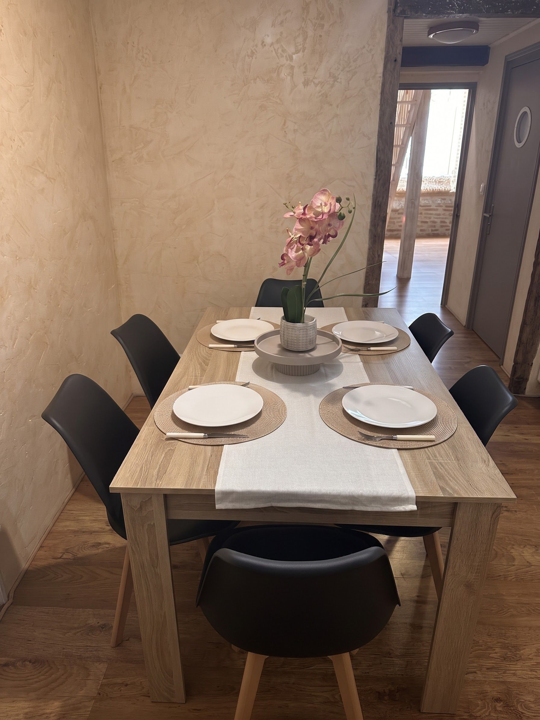 Una mesa de comedor dispuesta con platos, cubiertos y un centro de mesa.