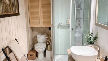 Un baño moderno con ducha envuelta en vidrio, un lavamanos espacioso y una lavadora.