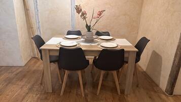 A dining table with six chairs, a vase with flowers, and a wooden floor.