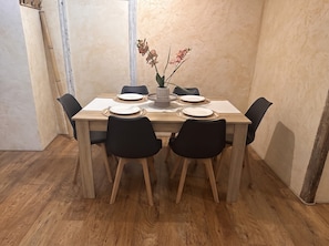 A dining table with six chairs, a vase with flowers, and a wooden floor. - New Listing (cahors)