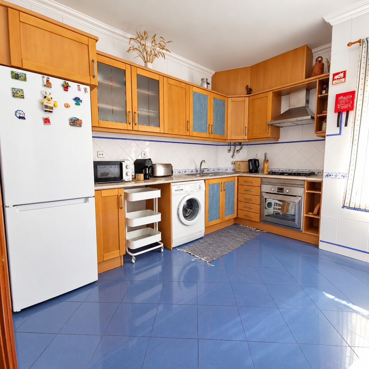 Une cuisine compacte avec des meubles en bois, un lave-linge, un four à micro-ondes et un réfrigérateur.