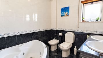 Une salle de bain moderne équipée d’une baignoire, d’un bidet, de toilettes et d’un lavabo.