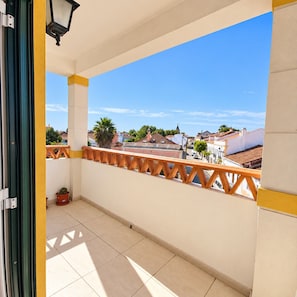 A balcony with a view of a town, a potted plant, and a lamp post. - Golegã Central by Gthouse (Golega)