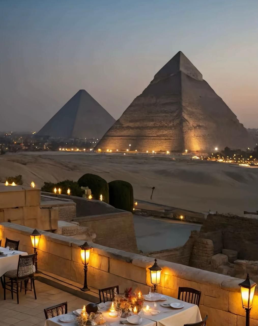 A dining area with tables and chairs, a view of the pyramids, and a desert landscape.