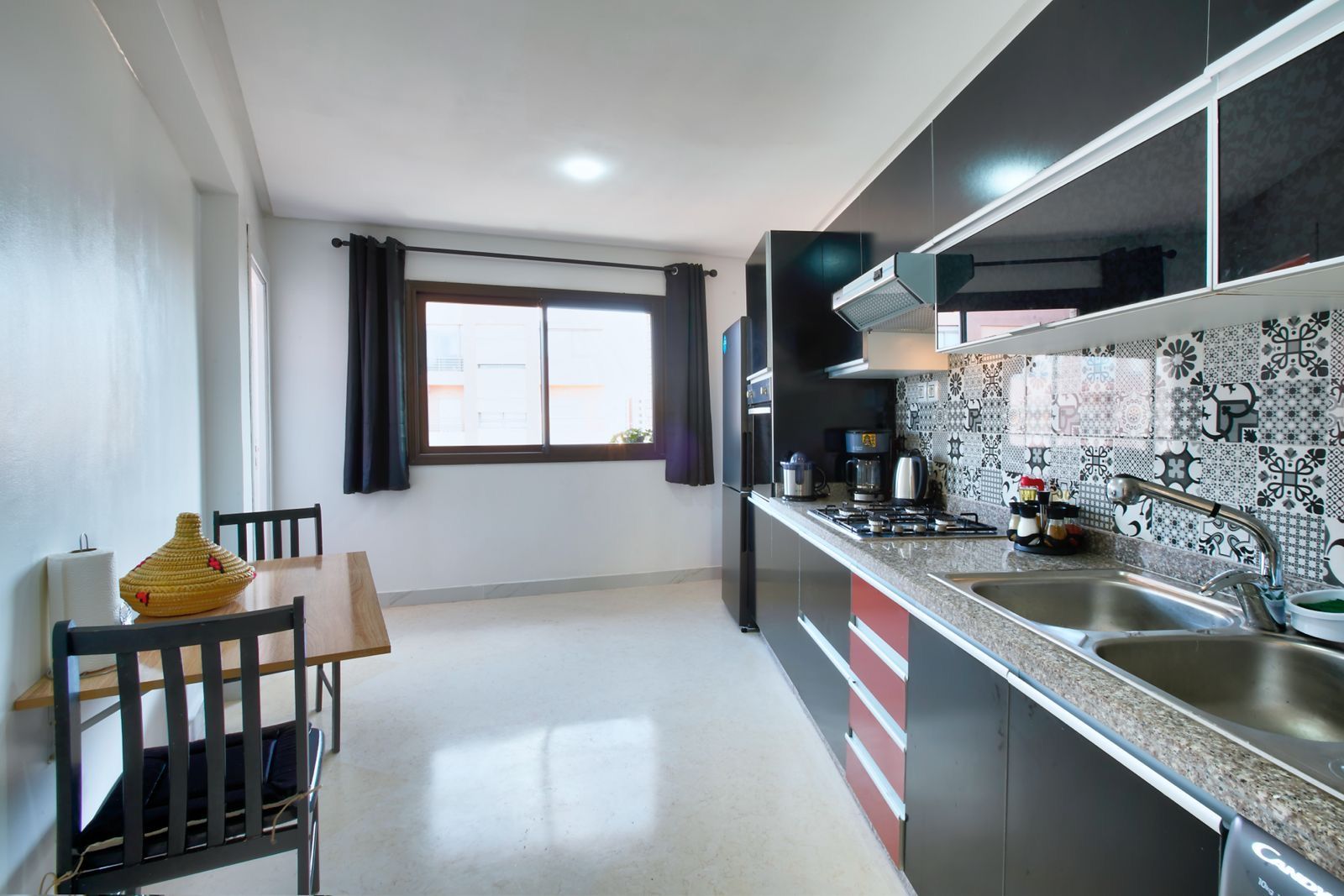 Une cuisine moderne avec un coin repas, une fenêtre avec des rideaux et un pare-feu en carreaux.