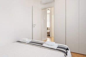 Ein Schlafzimmer mit einem Bett, einer Tür zu einem anderen Raum und einem sichtbaren Badezimmer.