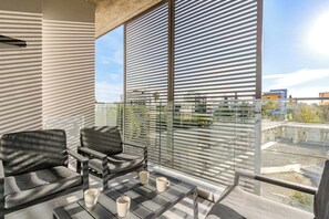 Ein Balkon mit einer Couch, Stühlen und einem Tisch mit Blick auf die Stadtlandschaft.