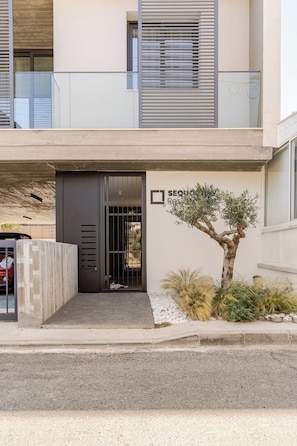 A modern building with a gated entrance, a small tree, and a sign that reads 'RESIDENCE.' - YAMAS Urban Living Sequoia Residence 3BR Penthouse (Lemesos)