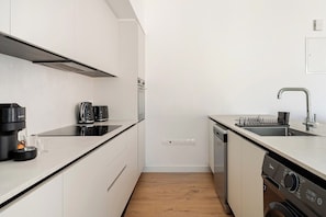 A modern kitchen with white cabinetry, a stainless steel range hood, a dishwasher, and a coffee machine. - YAMAS Urban Living Sequoia Residence 3BR Penthouse (Lemesos)