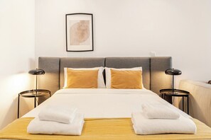A hotel room with a bed, two bedside tables, a headboard, and a framed picture on the wall. - Yamas Urban Living Olympia Suites Old Town Studio (Lemesos)