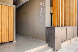 Une entrée d’hôtel moderne avec une enseigne indiquant « OLYMPIA SUITES ».