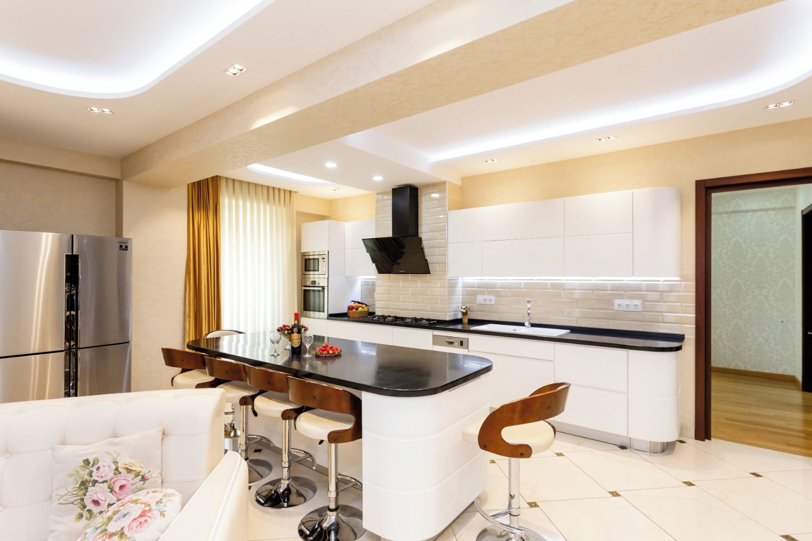 A modern kitchen with a central island, stainless steel appliances, and a dining area with bar stools.