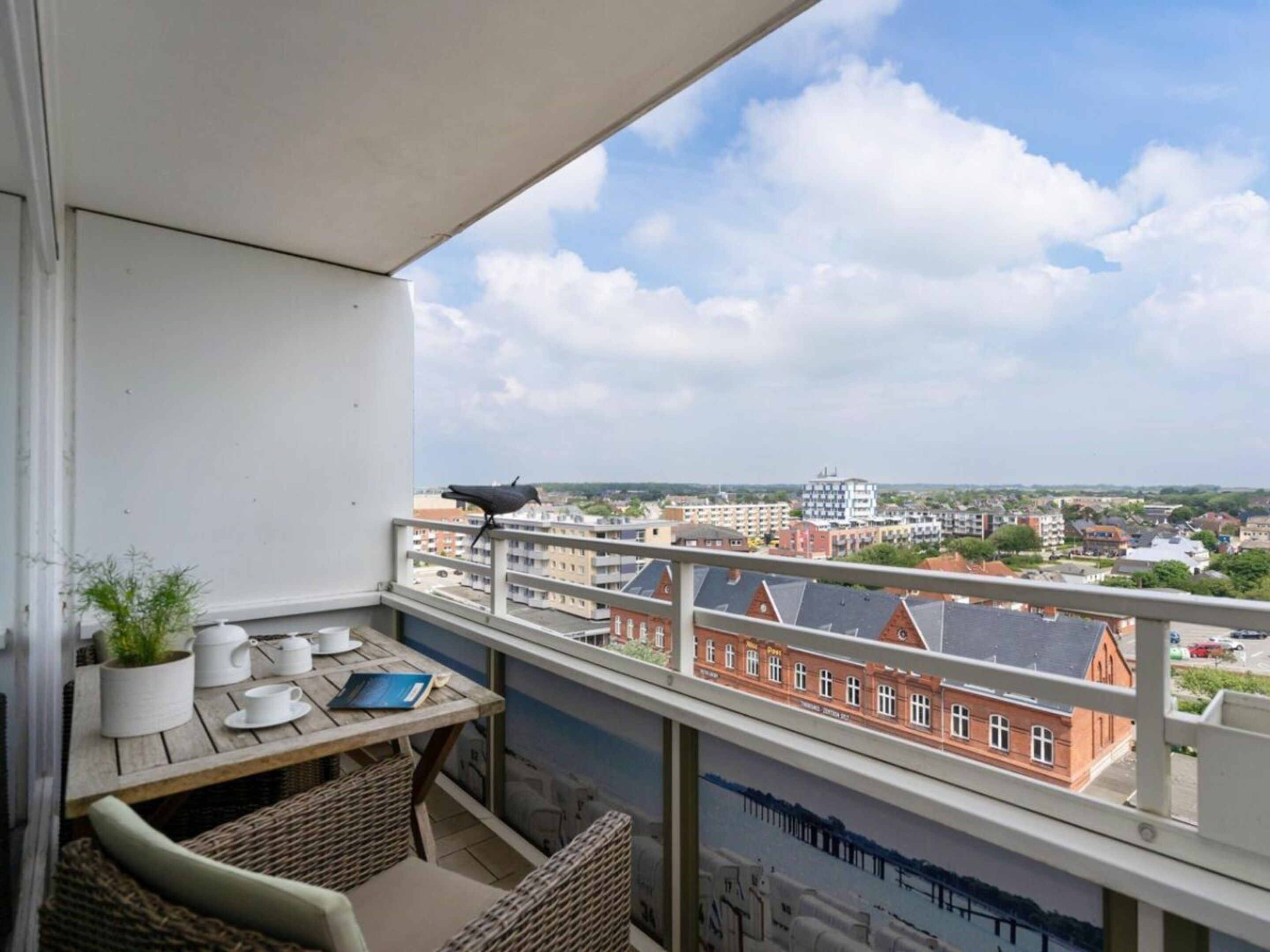 A balcony with a table, chairs, and a bird.