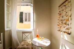 Ein Zimmer mit Tisch, Stuhl, einem Fenster mit Fensterläden und einer Wand mit aufgehängten Muscheln.