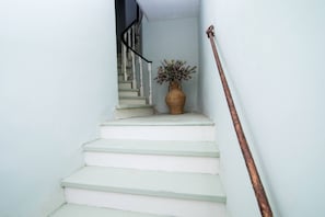 A staircase with white steps and a vase with flowers at the top. - Venetian Window Apartments CorfuEscapes (Corfu)