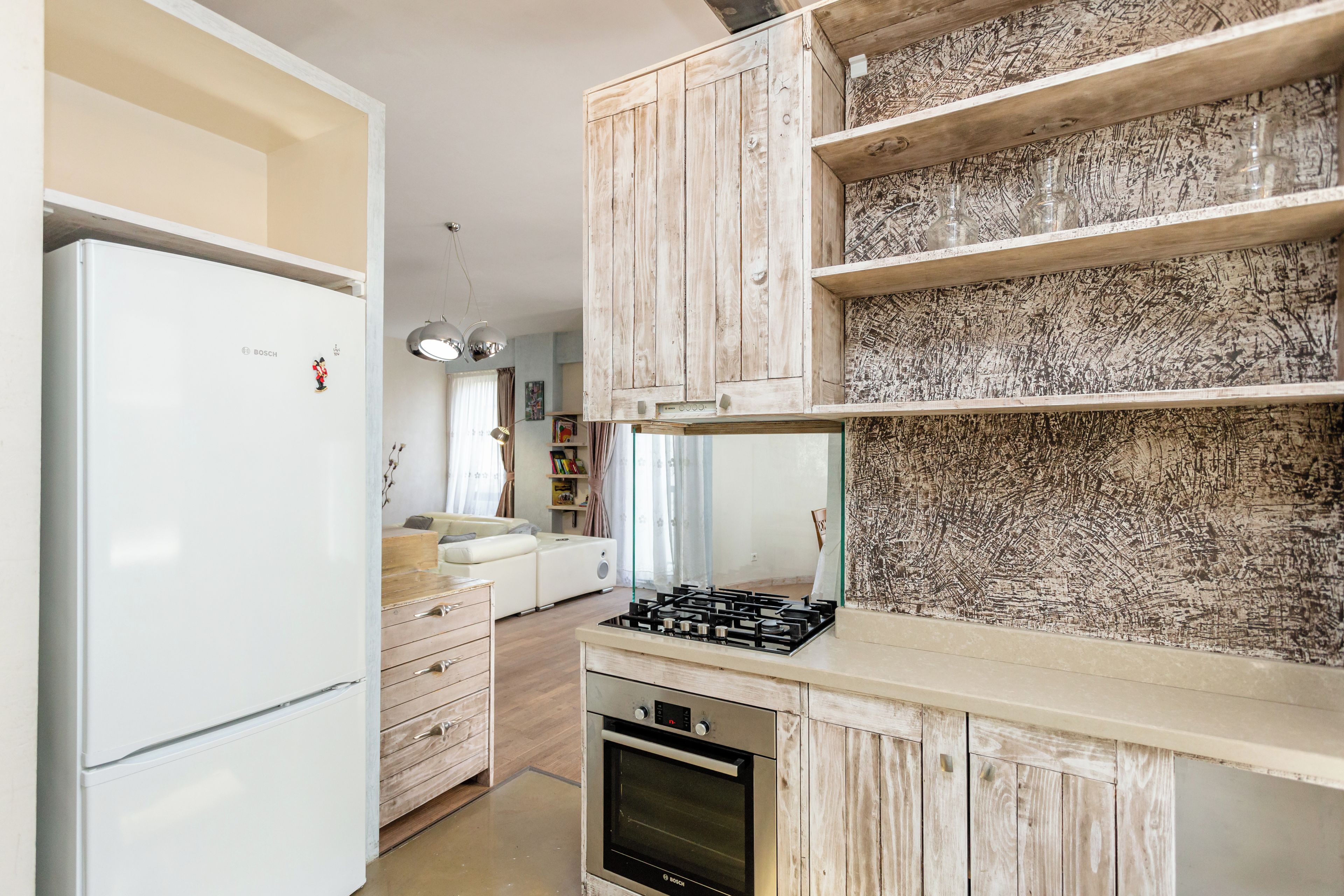 A kitchen with white cabinets, a Bosch refrigerator, and a gas stove.