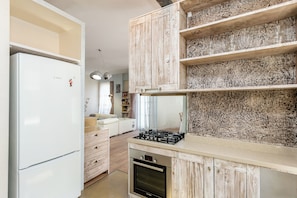 A kitchen with white cabinets, a Bosch refrigerator, and a gas stove. - Executive Central Loft (Tbilisi)