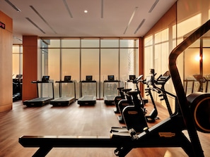Une salle de sport équipée de tapis de course, de vélos elliptiques et d’appareils de musculation.