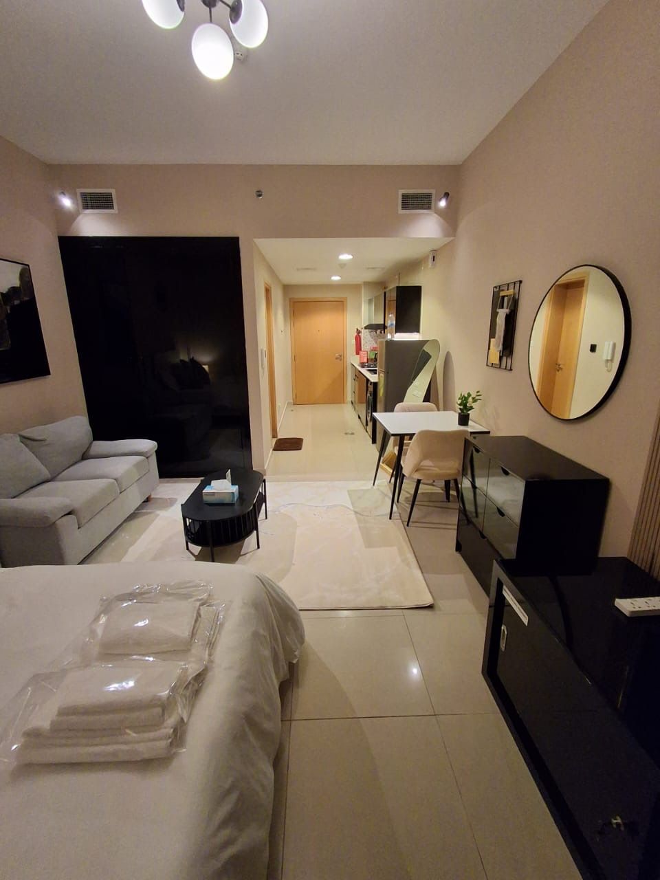 A hotel room with a bed, a sofa, a desk, a chair, and a television.