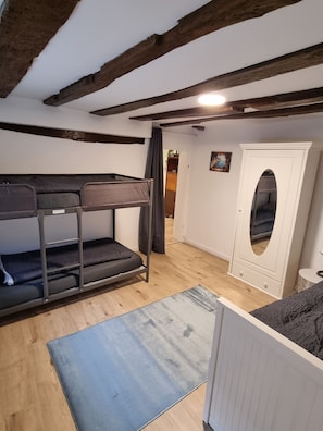 Une chambre avec un lit superposé, une armoire blanche et une petite table.