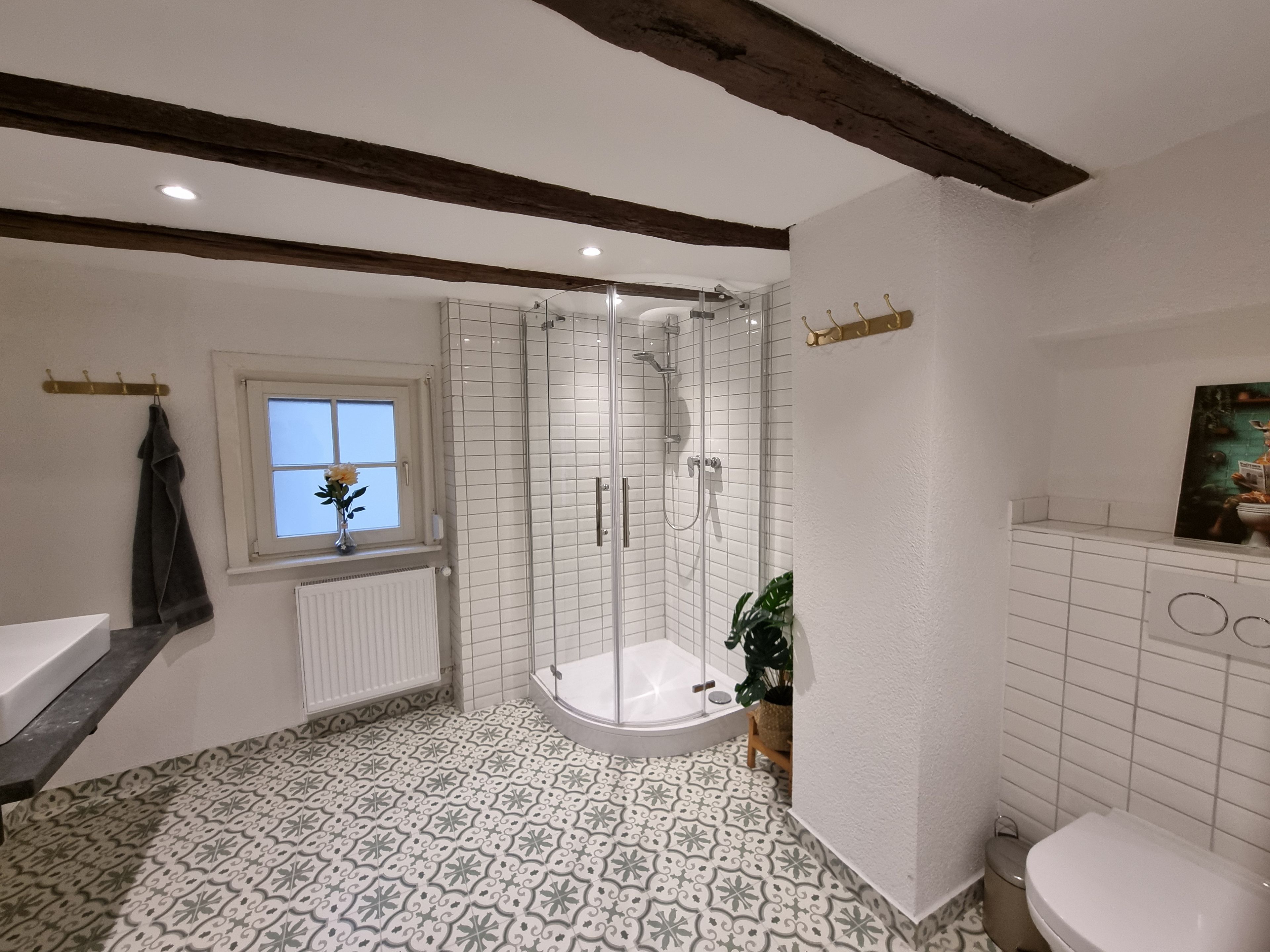 Ein Badezimmer mit Dusche, Toilette, Waschbecken und einem Fenster mit Handtuchhalter.