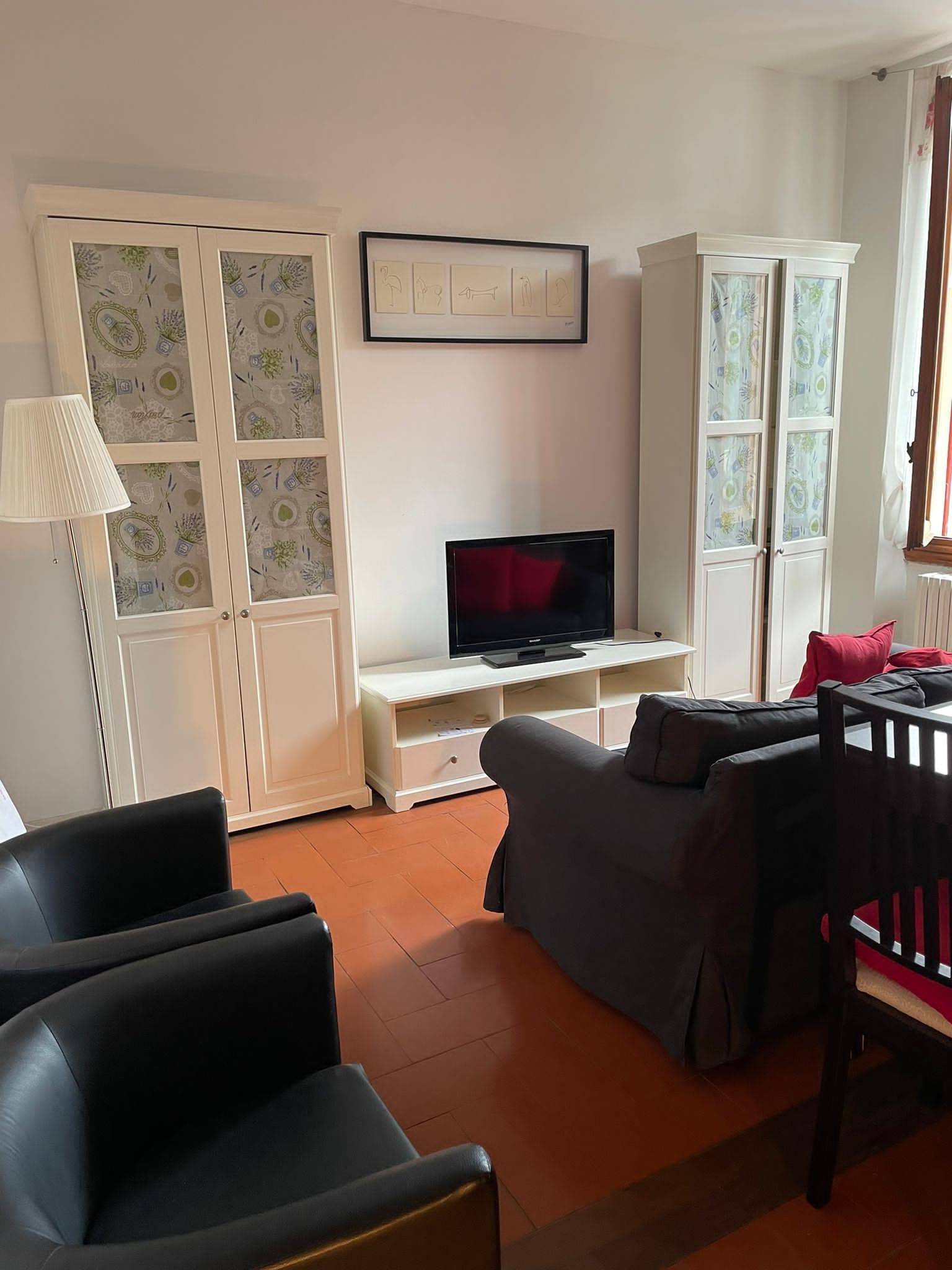 A living room with a television, a sofa, a chair, and a cabinet.